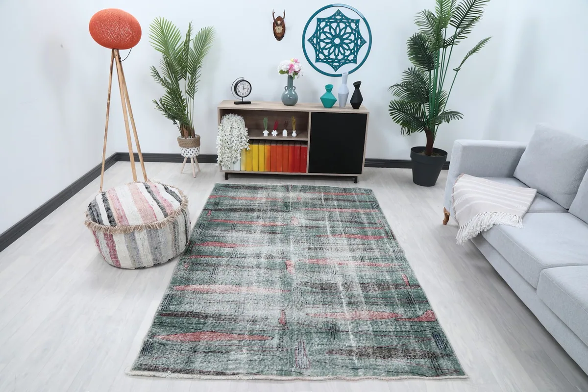 Green and rose vintage rug styled in a living room setting with a light sofa