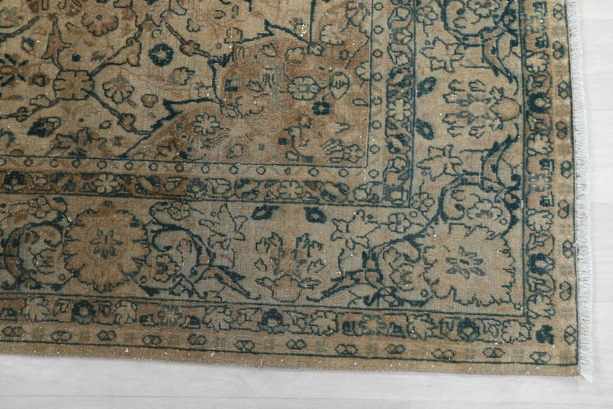 Detailed view of the rug's border design featuring blue and charcoal floral patterns on a beige background