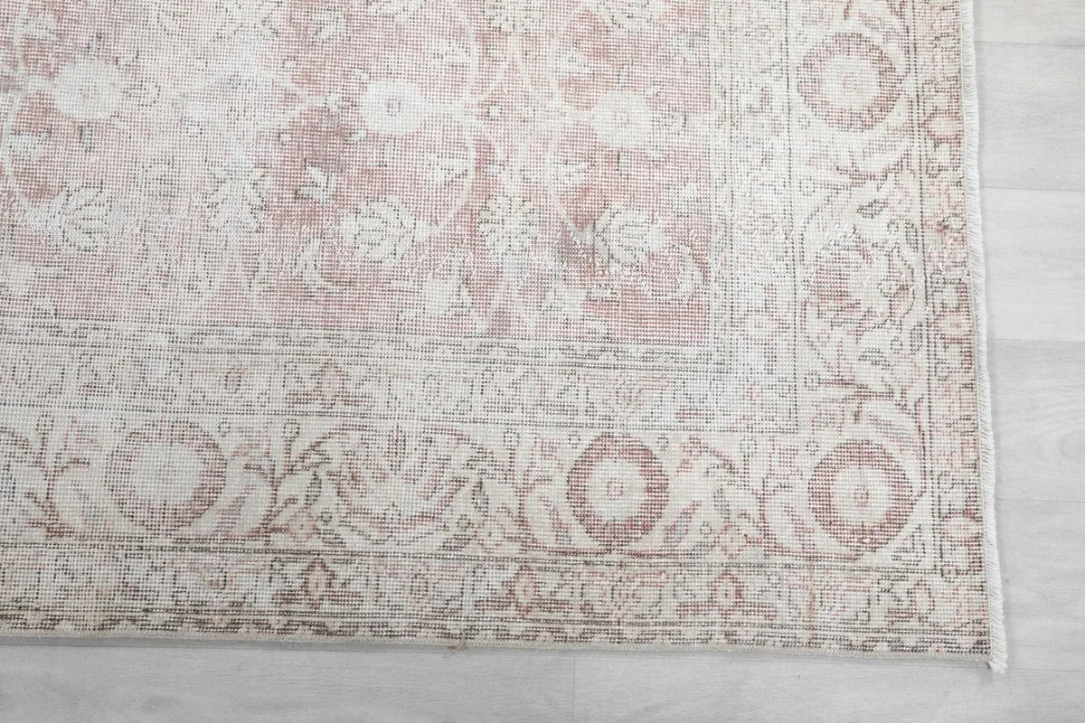 Close-up detail of the floral border design in faded rose and beige