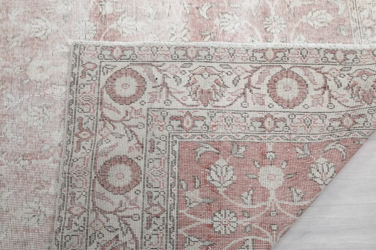 Detail of the rug's fringe and a corner, showing the construction and faded colors