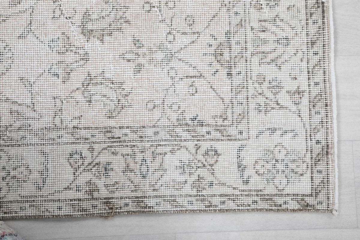 Detailed view of the corner and border pattern of the ivory and gray vintage rug