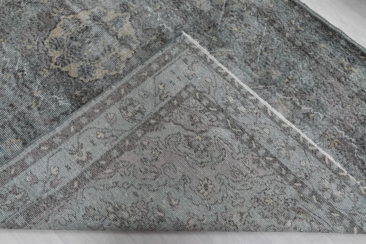 Folded corner of the rug, revealing the reverse side with intricate patterns and foundation