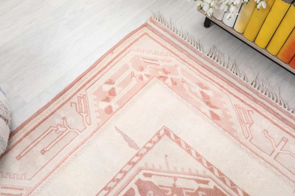 Corner detail showing the intricate geometric motifs in rose on the ivory background