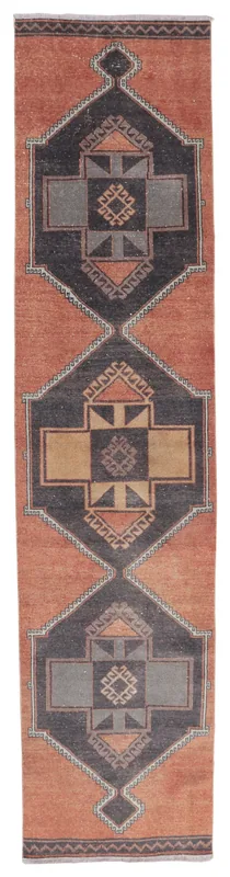 Full overhead view of a vintage rust and charcoal geometric Anatolian runner rug on a white background.