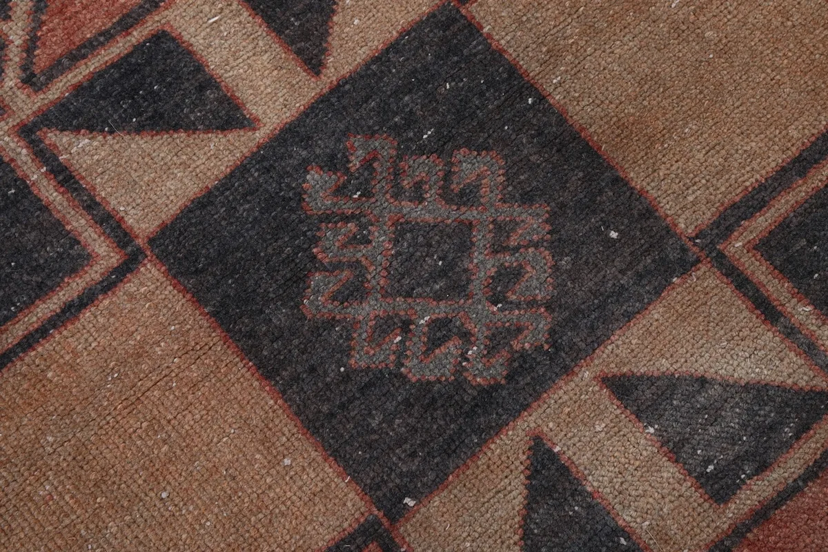 Very close detail of the hand-knotted pile and intricate tribal pattern within a charcoal diamond.