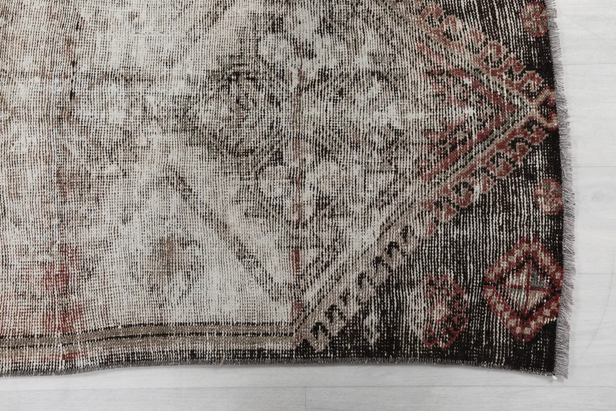 Detailed view of the rug's end, showcasing the dark brown and rust tones with geometric motifs