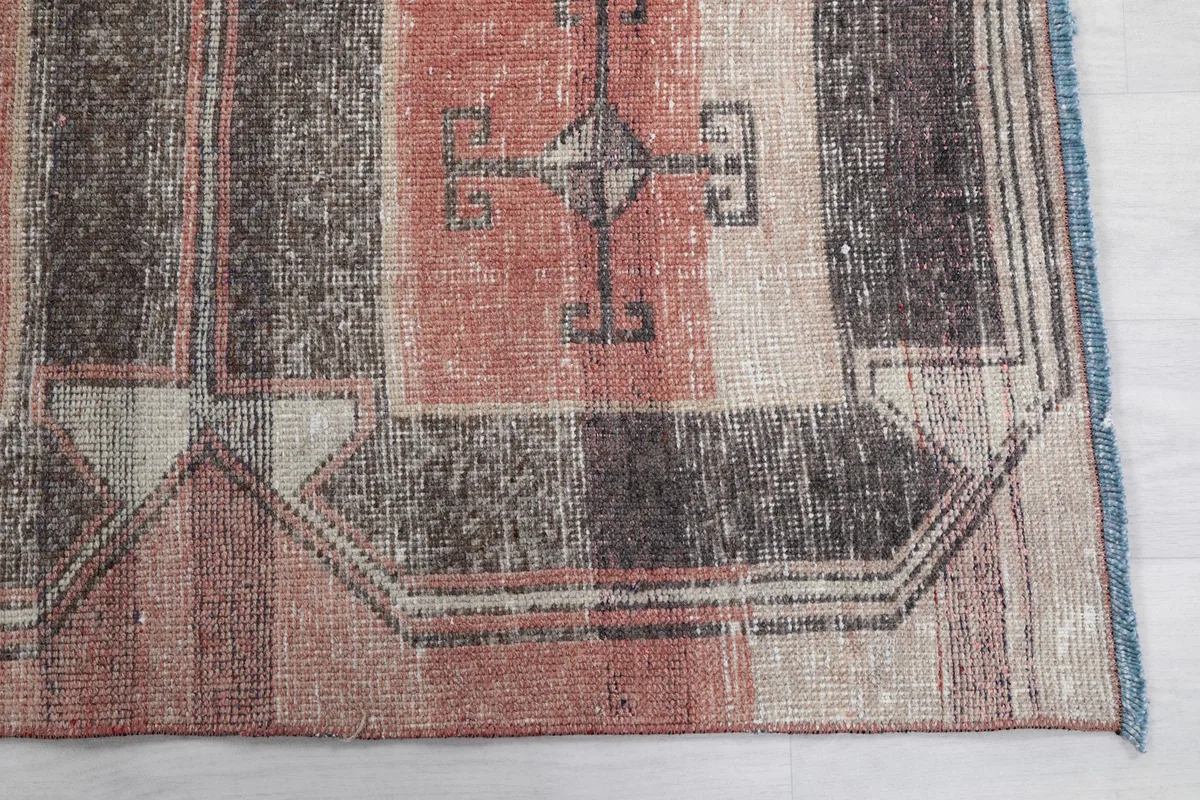 Detailed view of the rug's border and a corner, showing faded colors