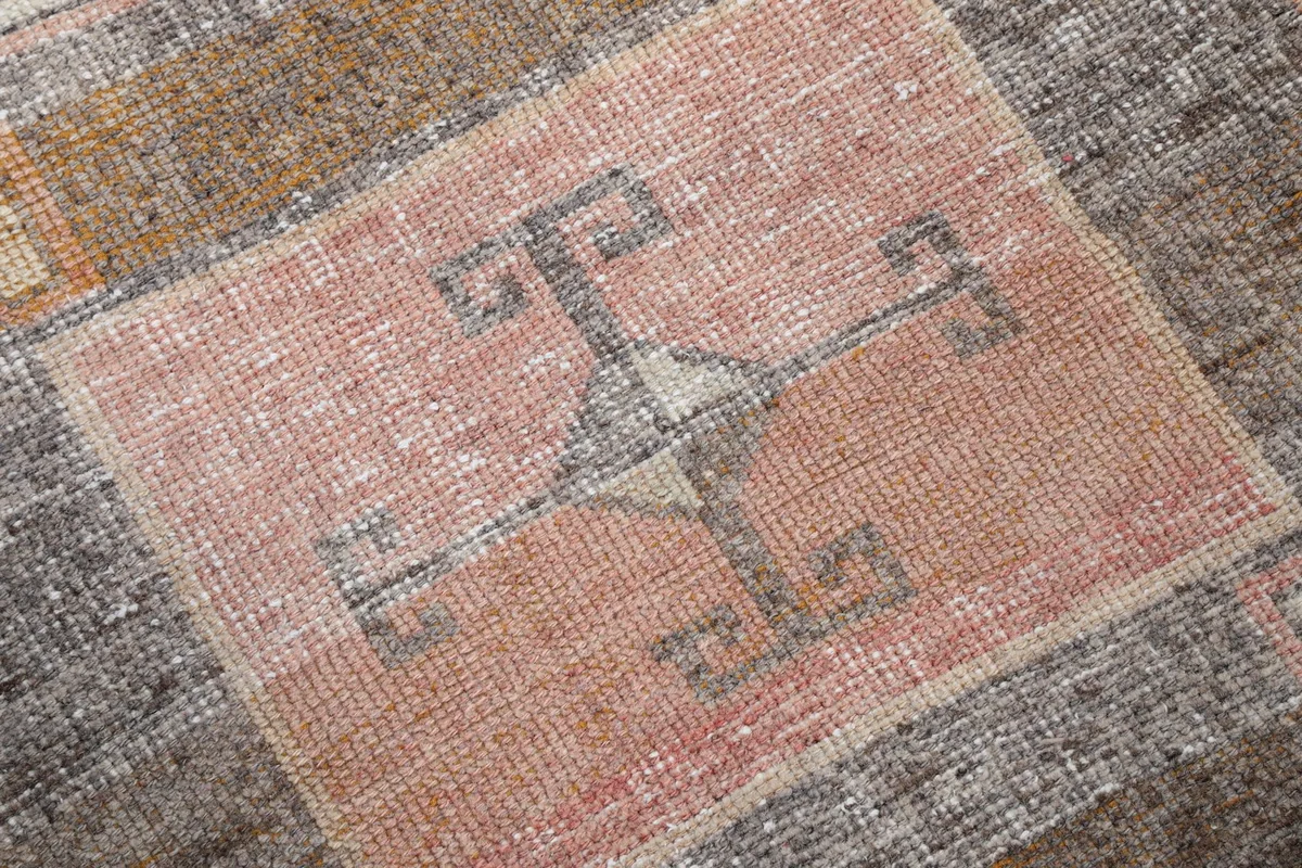 Close-up of a central geometric motif in orange and charcoal with subtle wear