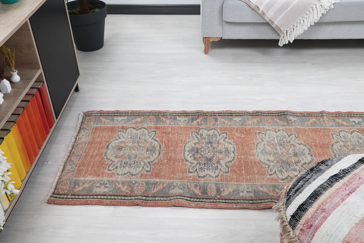 Overall view of the runner rug in a room, showcasing its length and distressed appearance.