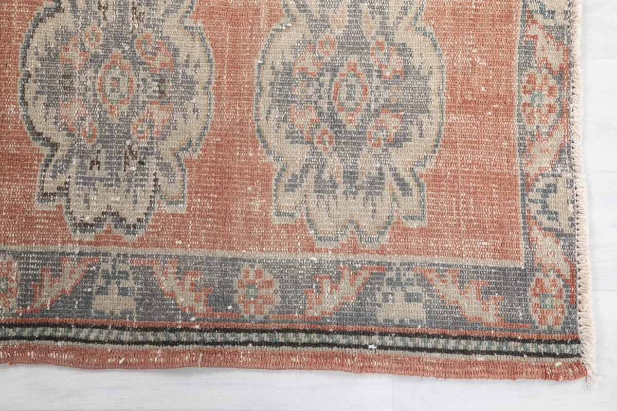 Detail of the rug's border and a medallion, highlighting the faded rust and gray tones.