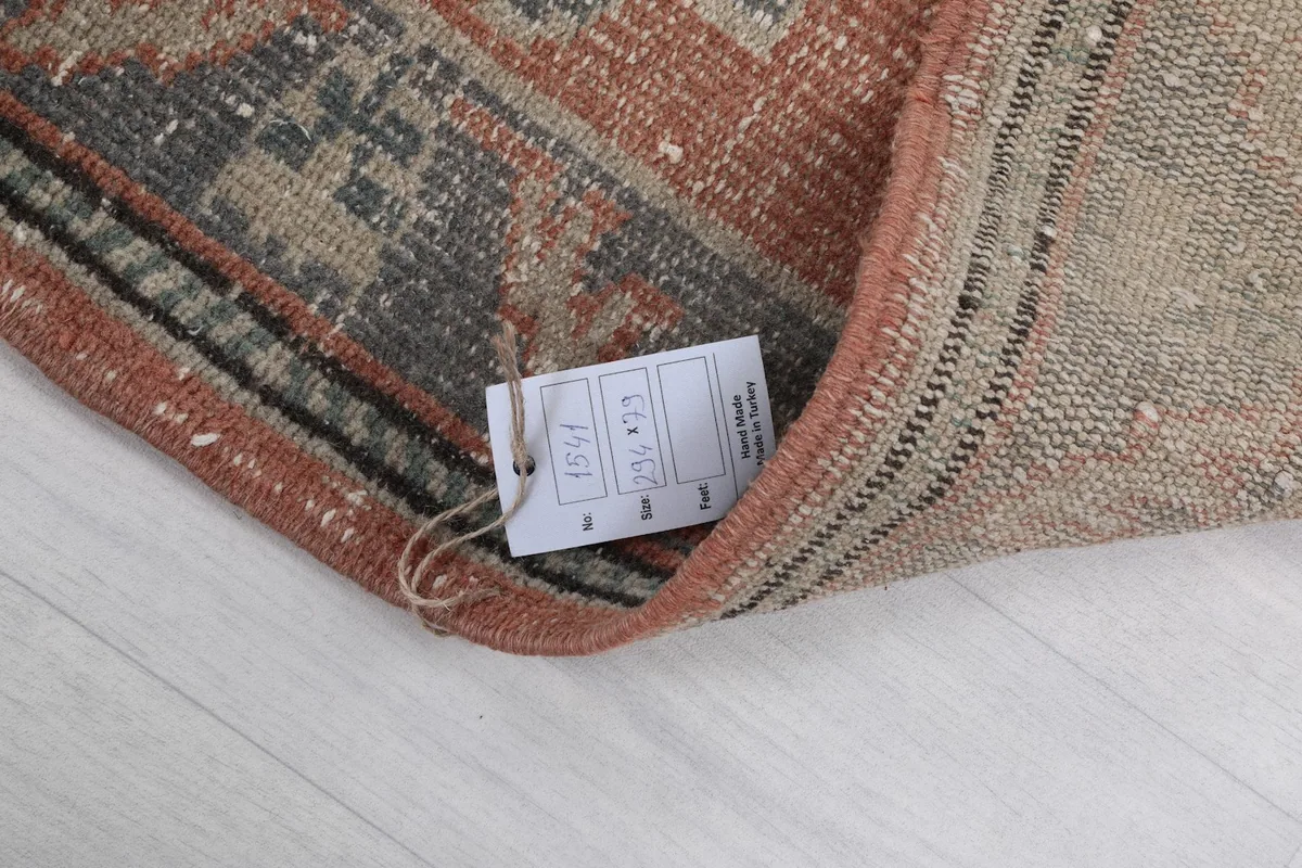Rug tag attached to the back, indicating it is a hand-knotted vintage wool rug.