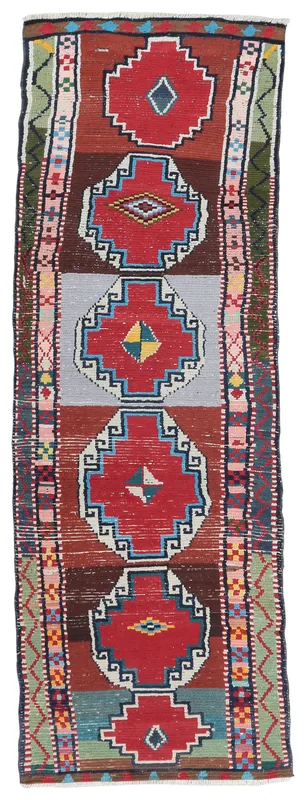 Full top view of the vintage Anatolian runner rug with red geometric medallions and multicolor details.
