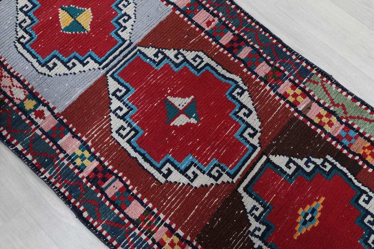 Close-up of a red geometric medallion with blue and white outlines, showing the wool pile texture.