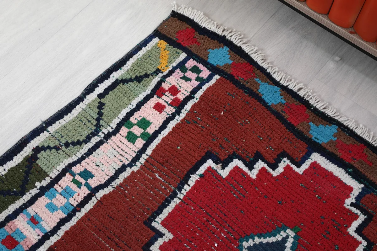 Corner detail of the rug's border, showcasing the varied colors and patterns along the edge.