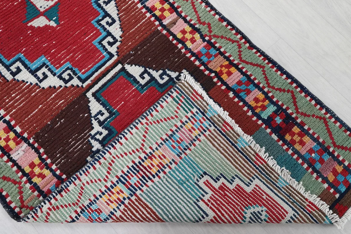 Folded corner of the rug revealing the cotton foundation and the reverse side of the hand-knotting.