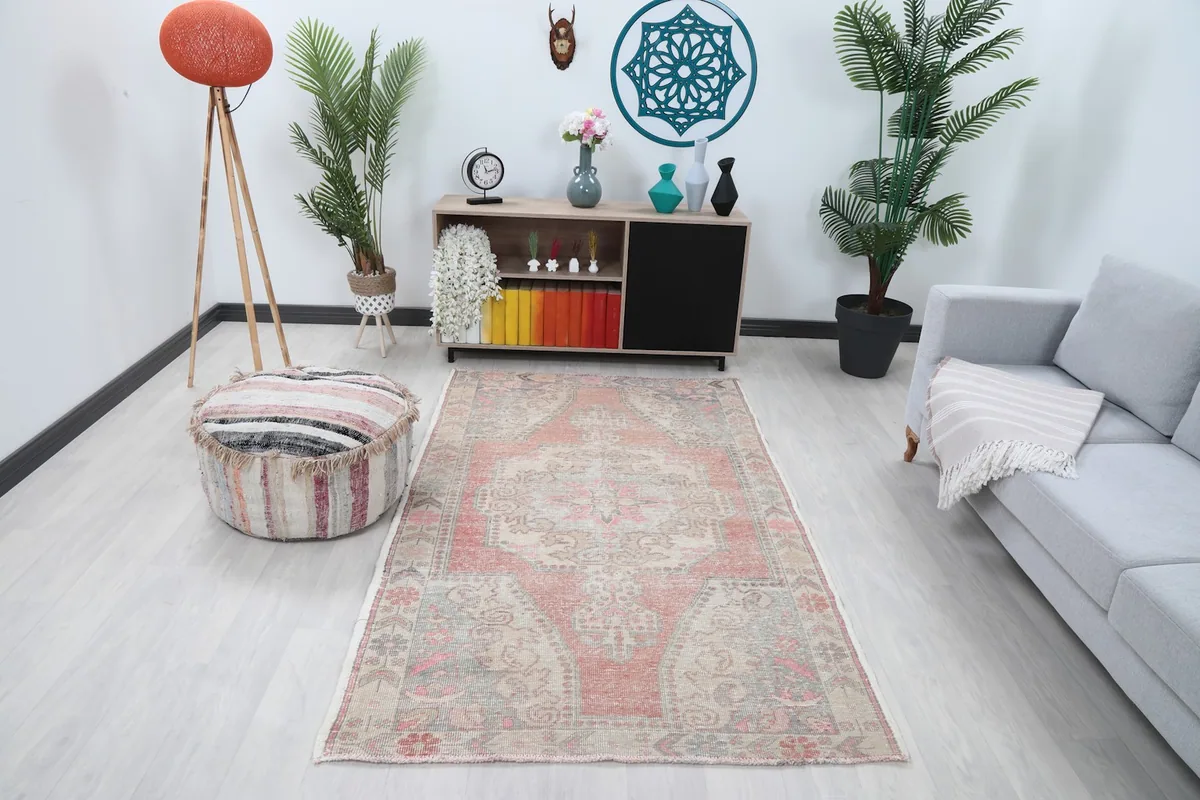Vintage rust and beige rug styled in a living room setting with a sofa and pouf