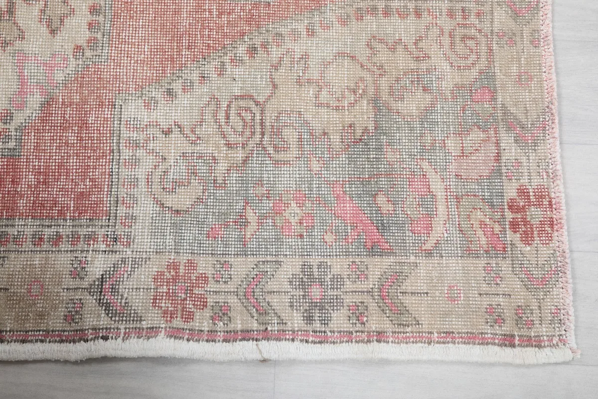 Detailed view of the rug's border and corner, showing geometric and floral motifs in rust, blue, and beige