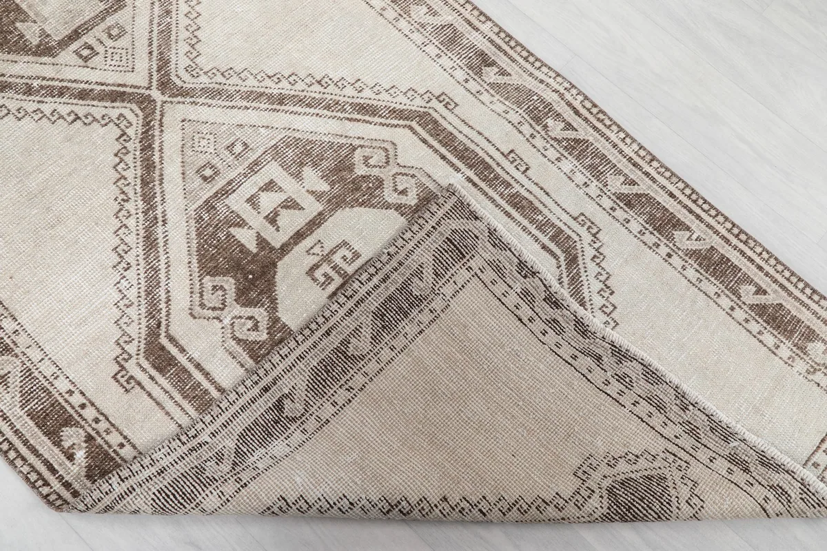 View of the rug folded back to show the cotton foundation and the reverse side of the knots.