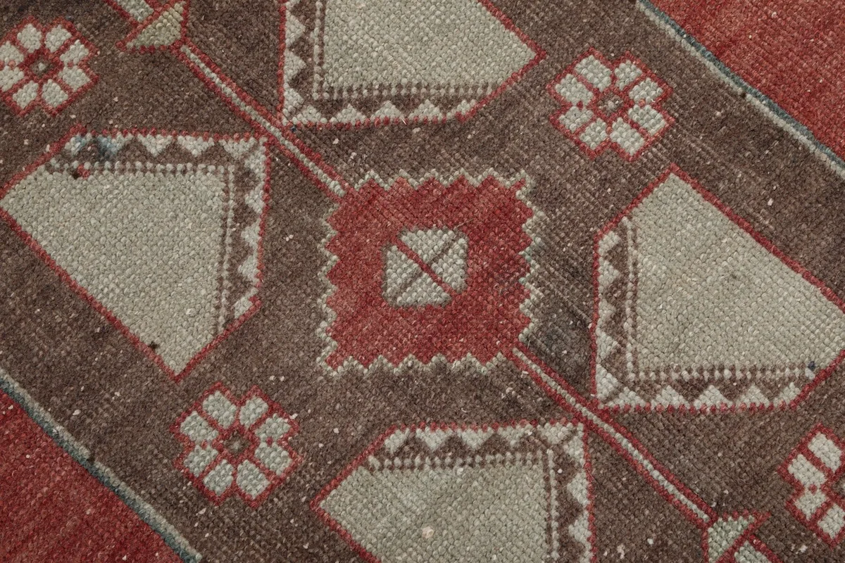 Close-up of a central geometric motif in red and beige, showing the hand-knotted wool pile texture