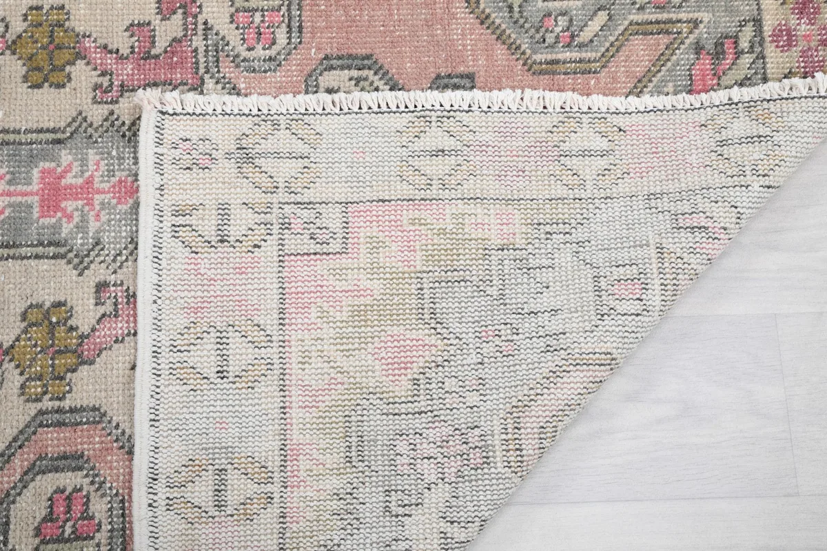 Corner of the rug folded back, showing the back of the weave and fringes.