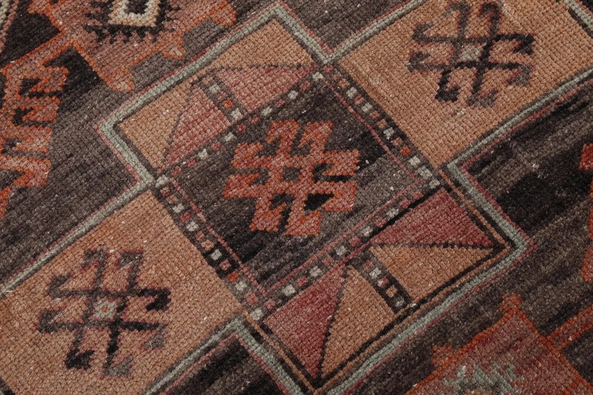 Intricate detail of the hand-knotted wool pile and tribal symbols in tan and rose