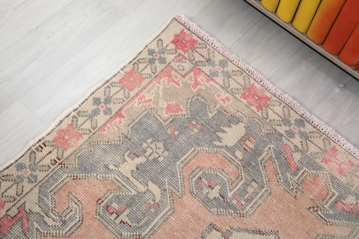 Detail of the rug's border with repeated floral and geometric elements in muted colors