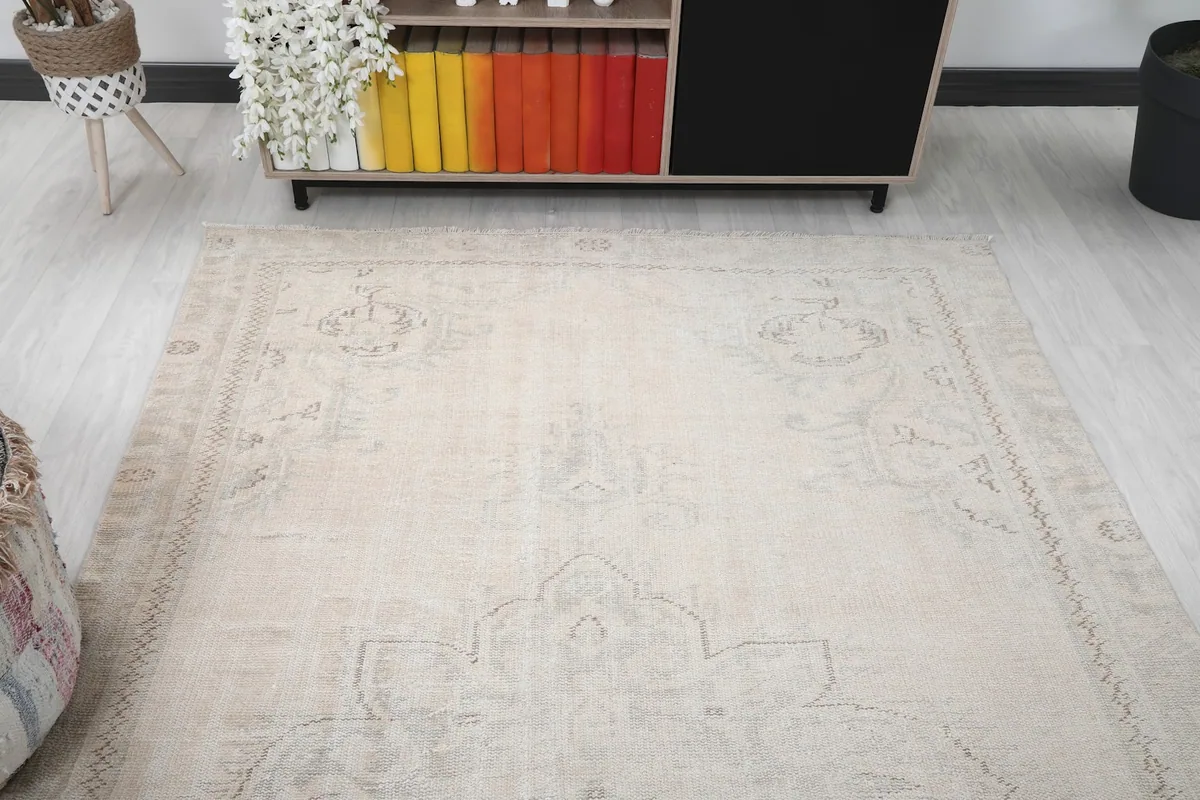 Overhead angle shot of the cream vintage rug, focusing on the upper half and its soft color.