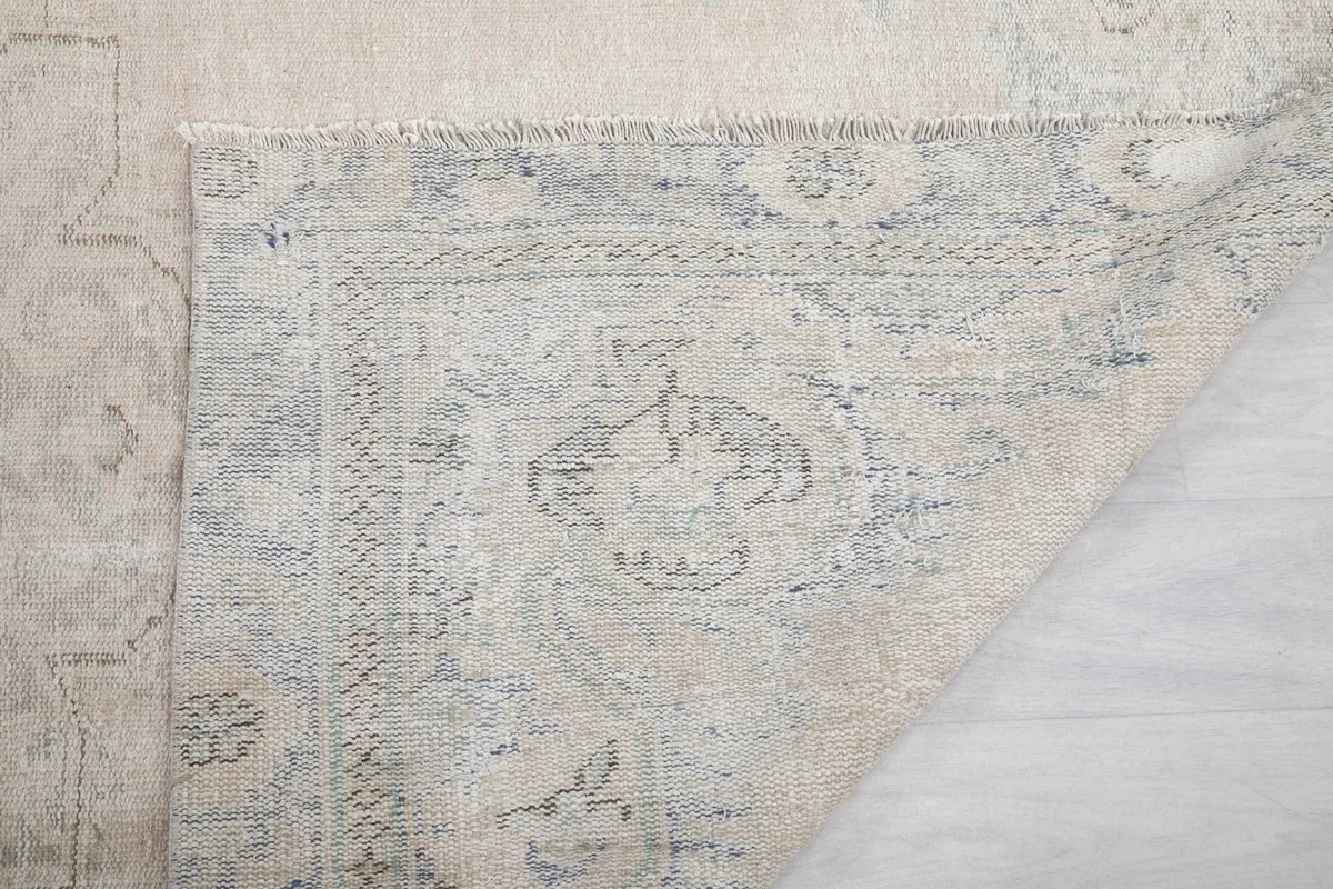 Close-up of the back of the rug, showing the intricate knotting and the muted colors of the foundation.