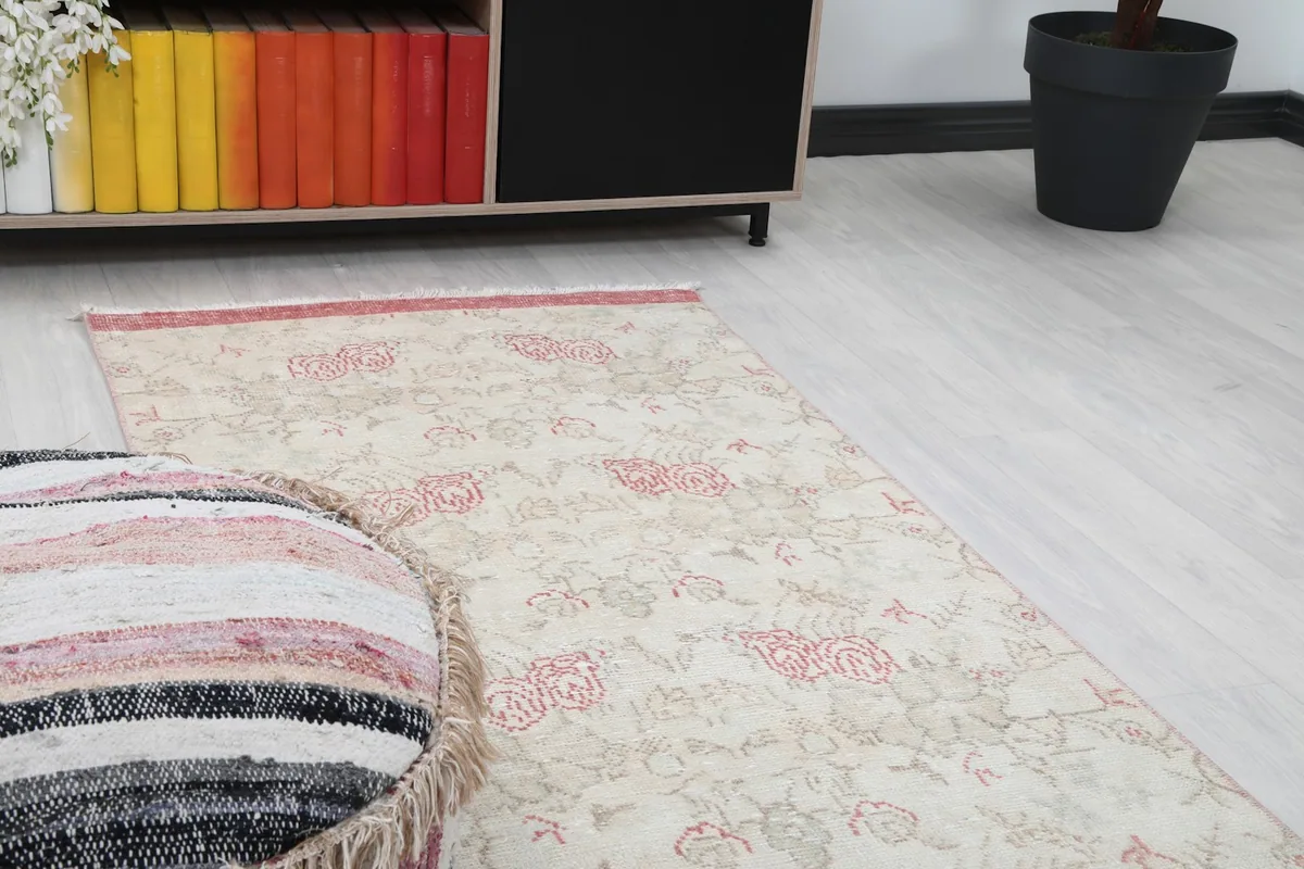 Close-up angled view of the rug's pattern and colors, with a pouf in the foreground.
