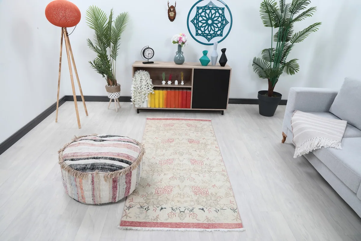 Overhead view of the rug placed in a modern living room setting with a light grey sofa and a striped pouf.