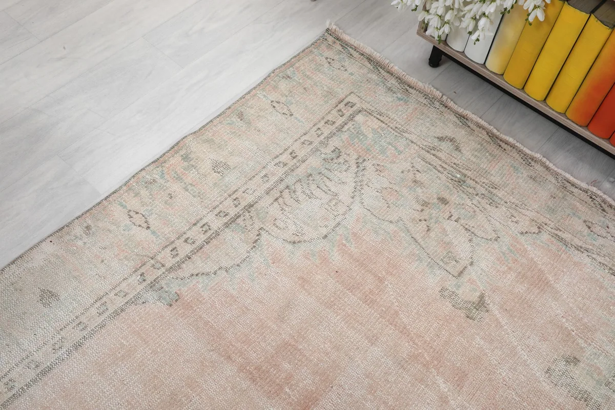 Corner view of the rug, showing the intricate border design and the soft color palette.