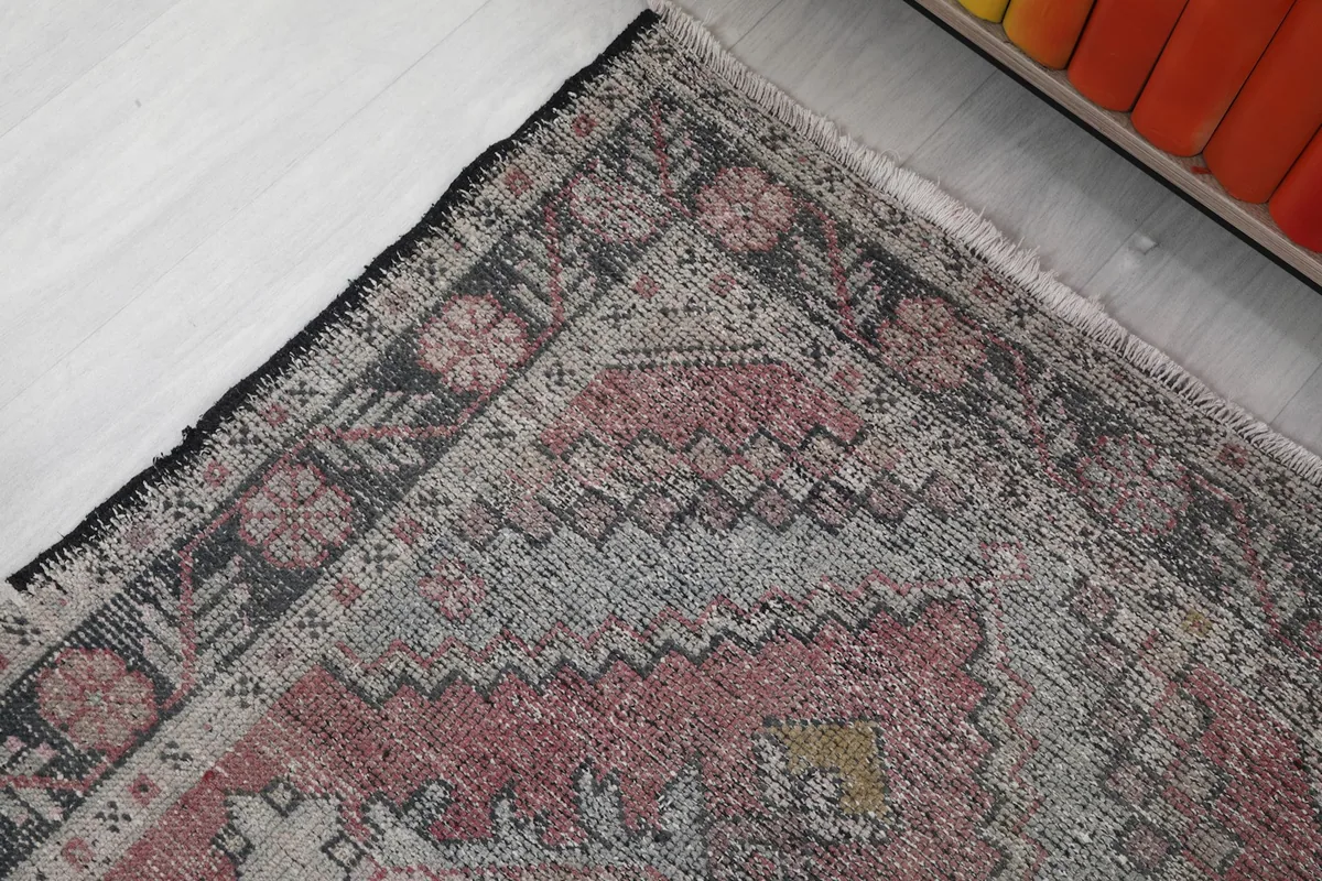Detailed view of the charcoal border with floral motifs and the faded rose main field