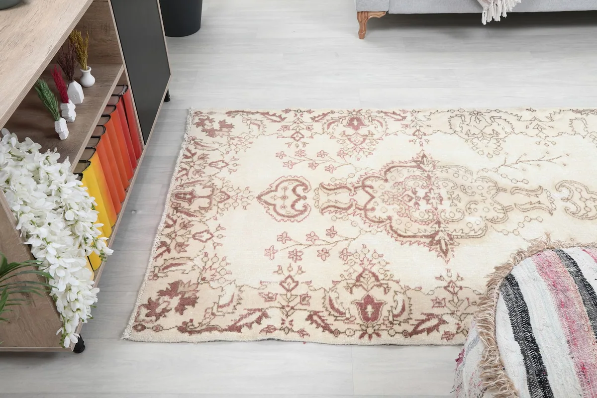 Angled view of the vintage rug on a light floor, showing its placement in a room