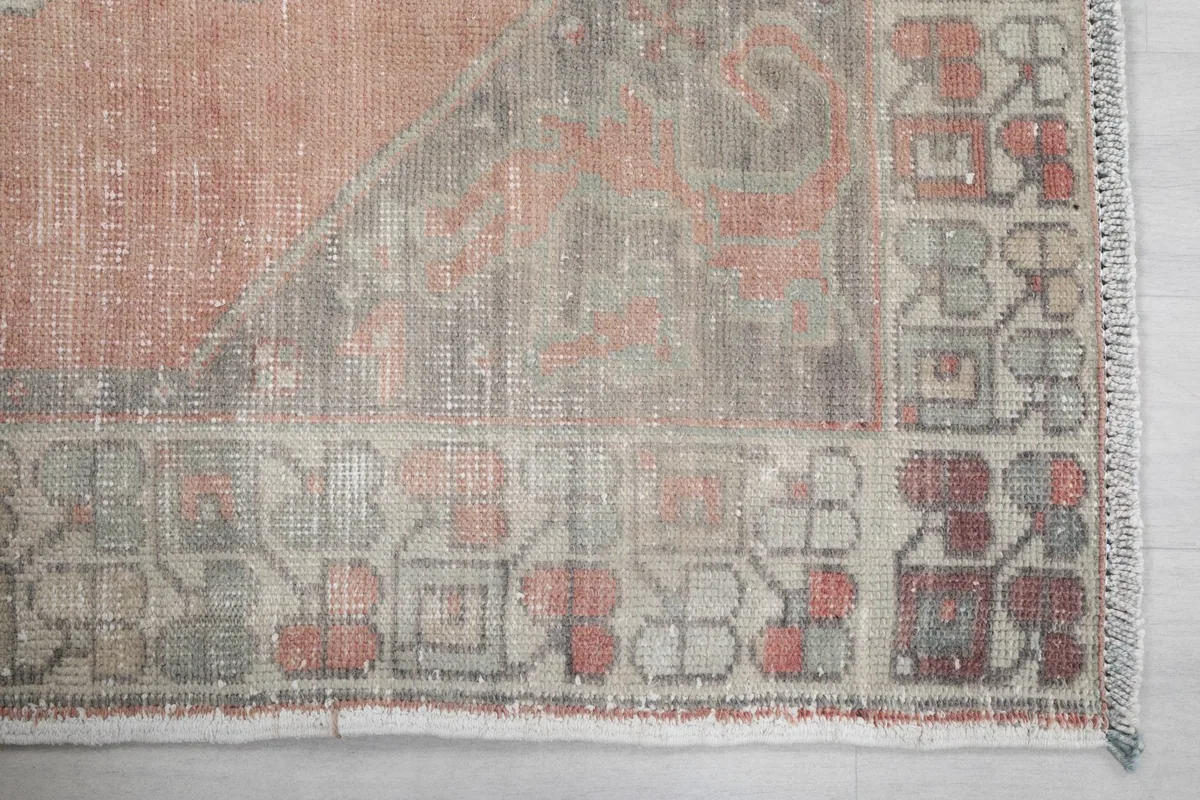 Detailed view of the rug's border with geometric and floral-inspired motifs in gray and rust tones