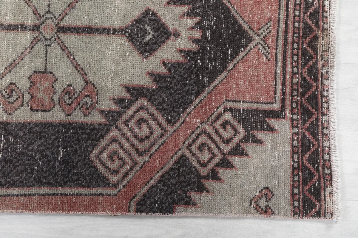 Detail of the runner's border and corner, showing the distinct geometric designs and faded rust color.