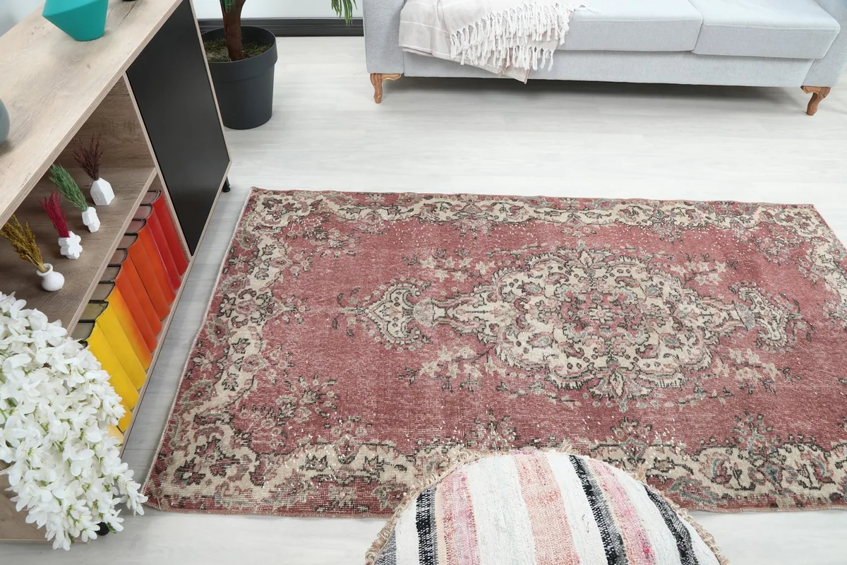 The rose rug placed in a room, offering perspective on its small size and decorative impact.