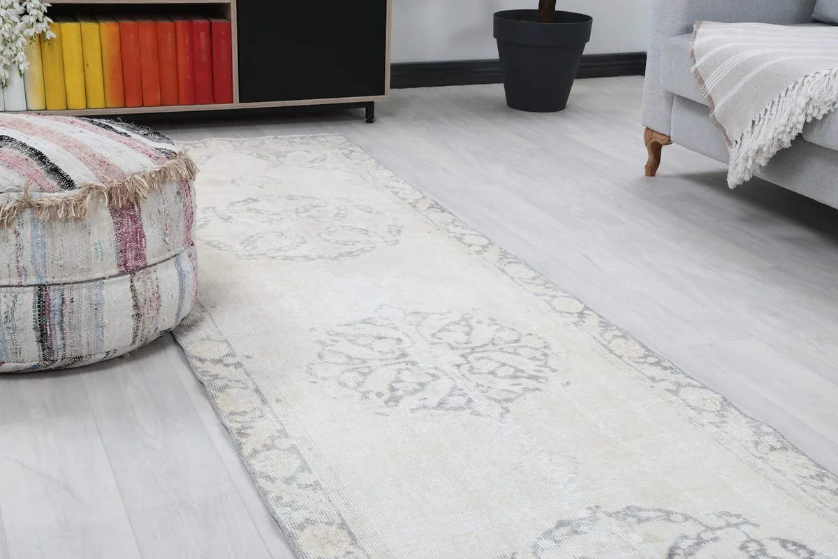 Close-up of the rug's central medallion and border, showing ivory and gray patterns with gentle wear