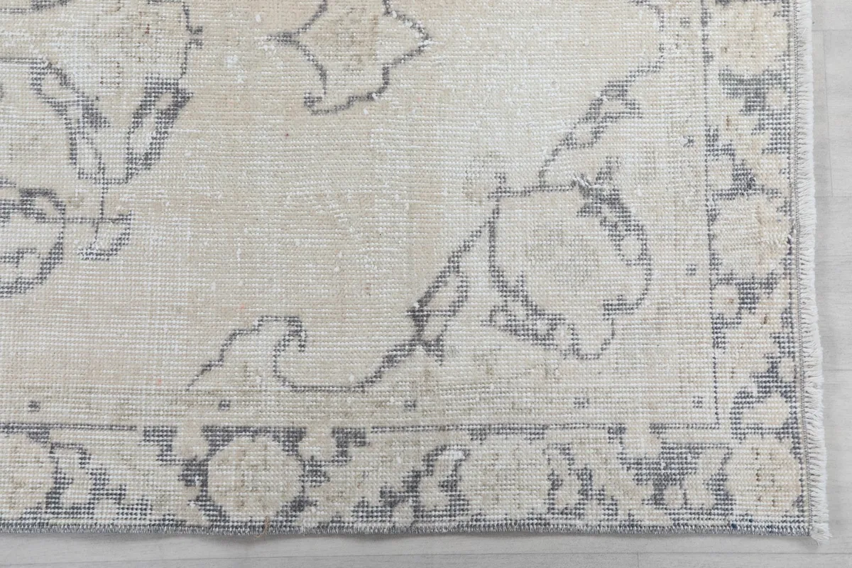 Detailed shot of a corner of the rug, revealing the intricate gray and beige floral border design