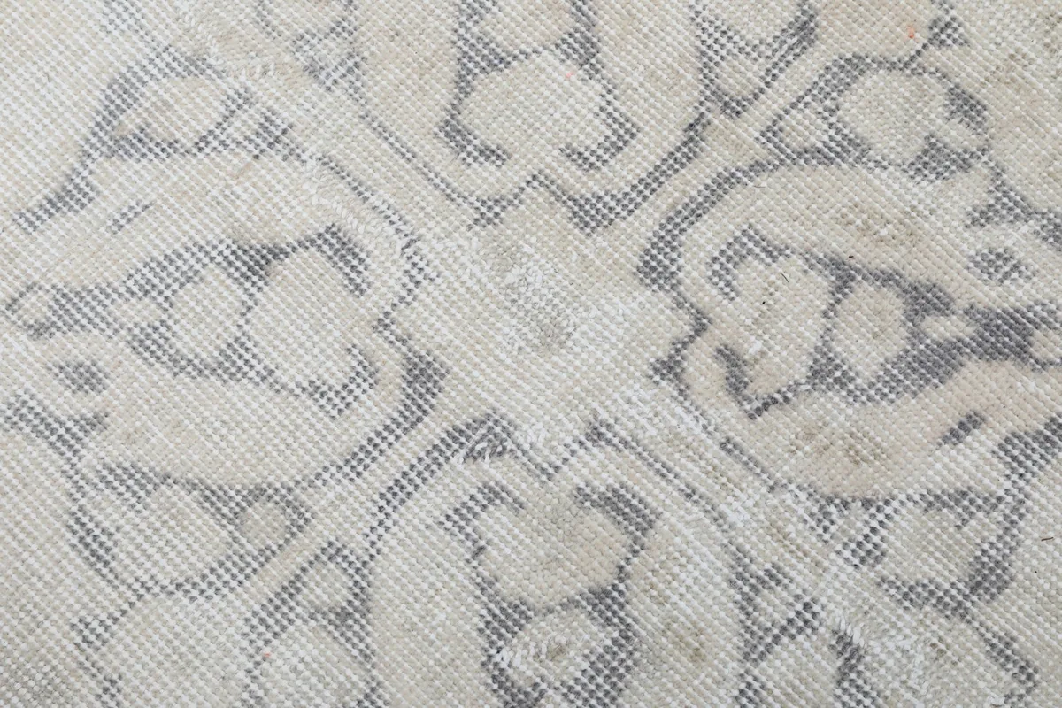 Macro view of the hand-knotted wool pile, showing the texture and subtle color variations of ivory and gray