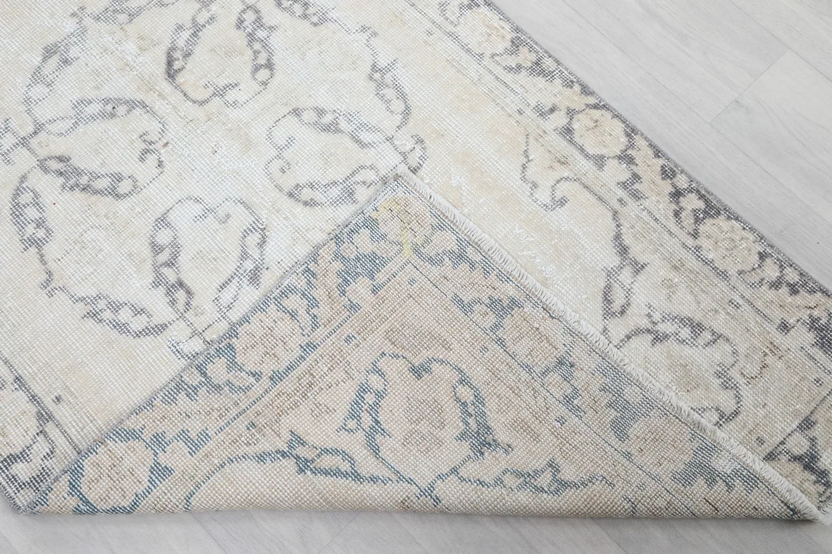 Flipped corner of the rug revealing the cotton foundation and the reverse side of the hand-knotted wool