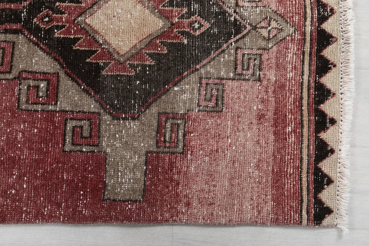Detail view of the rug's corner, highlighting the geometric motifs and subtle color variations.