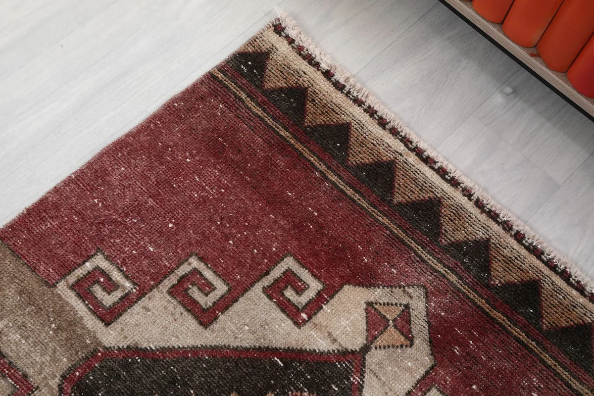 Detail of the rug's border and fringe, with a pattern of triangles and a meander design.