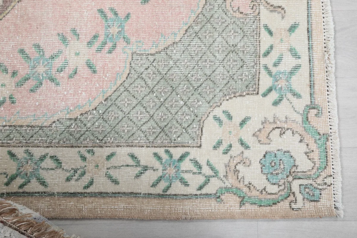 Close-up detail of the corner of the rug, showing the green and ivory border design