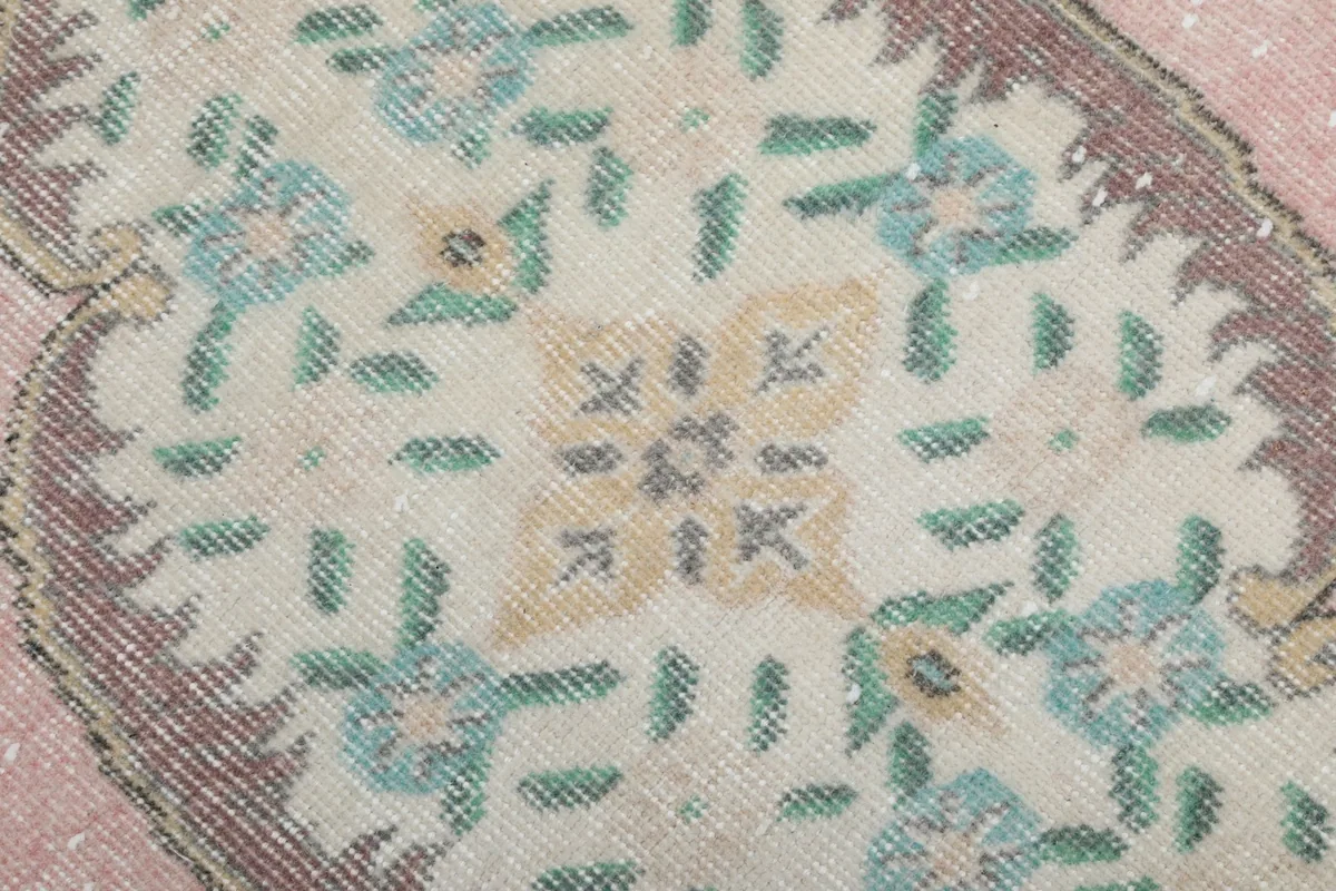 Detailed view of the central medallion's intricate floral pattern in ivory, gold, and light blue