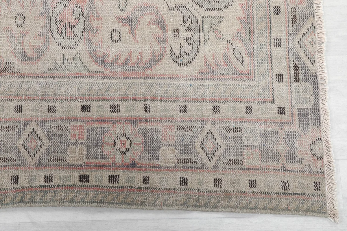 Close-up of the rug's border with gray and beige geometric patterns and fringe