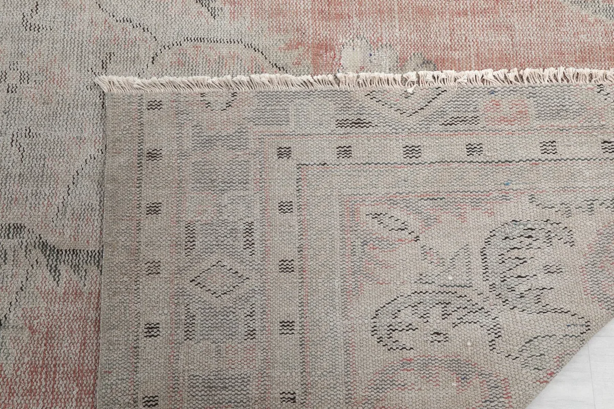 Close-up of the rug's corner, showing the natural fringe and border details