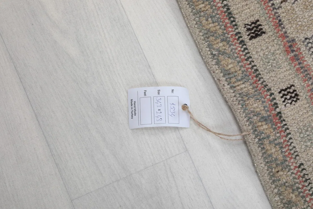 Product tag with rug dimensions and origin information on a light floor