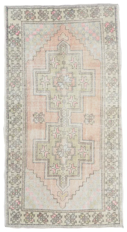 Full overhead view of the pink and green geometric vintage Anatolian rug on a white background.