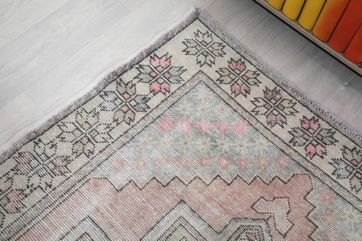 Detail of the rug's upper corner and border, showing the faded colors and distinct tribal motifs.