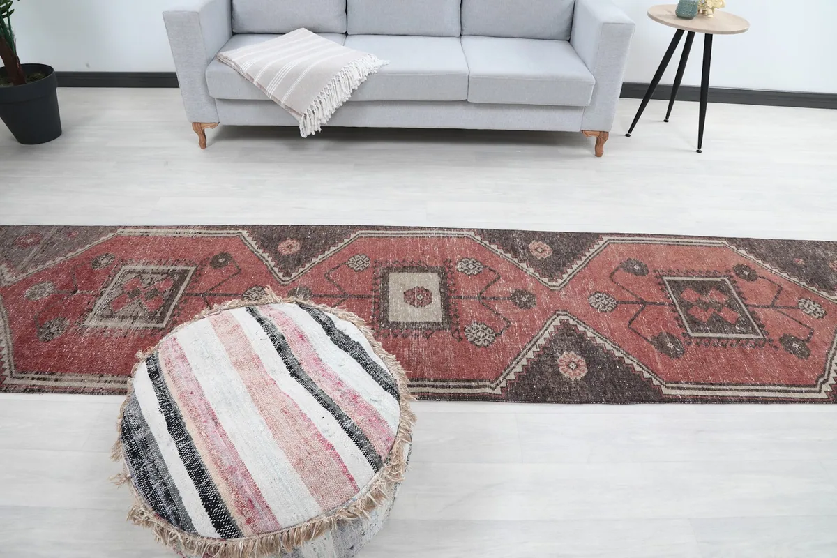 Overhead view of the rug and a round pouf in a room with a light grey sofa